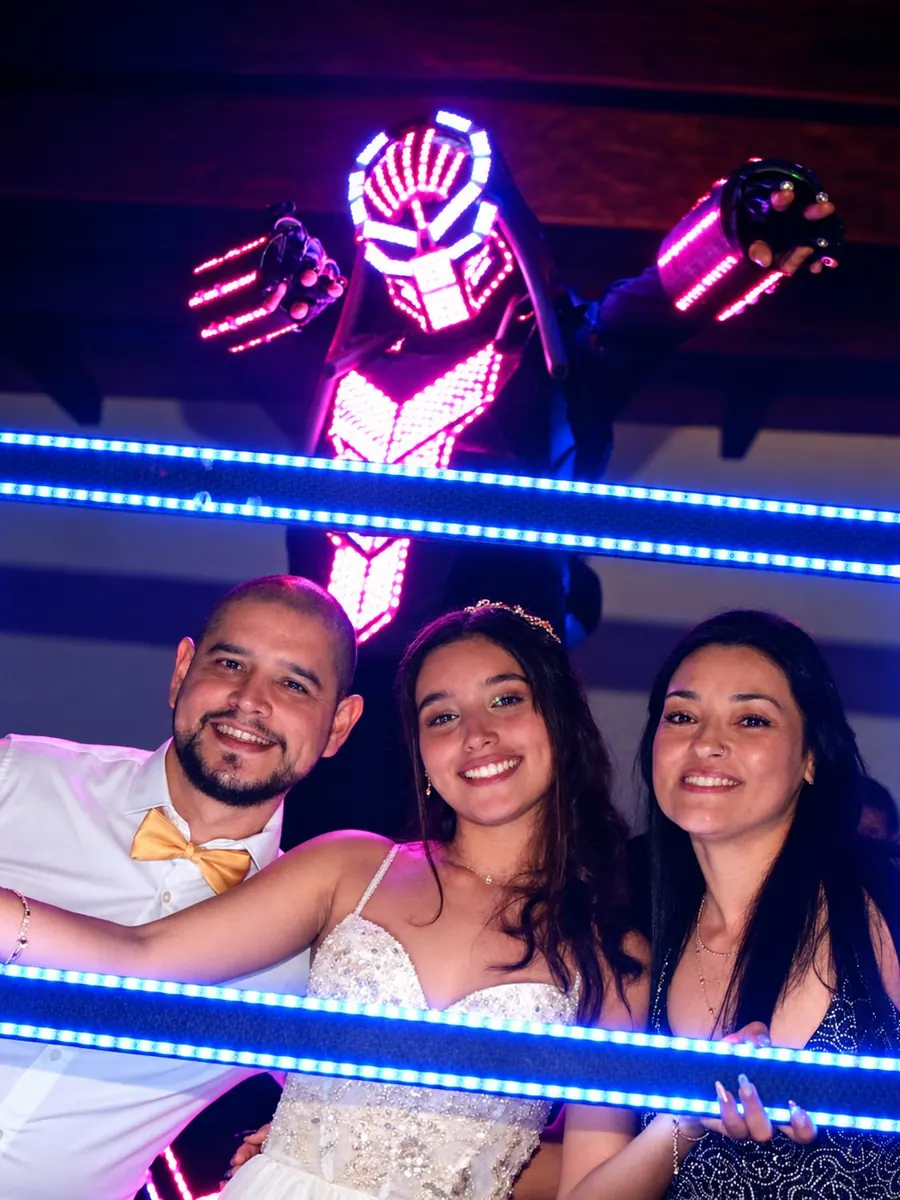 Quinceañera con su familia posando en un marco de luces LED